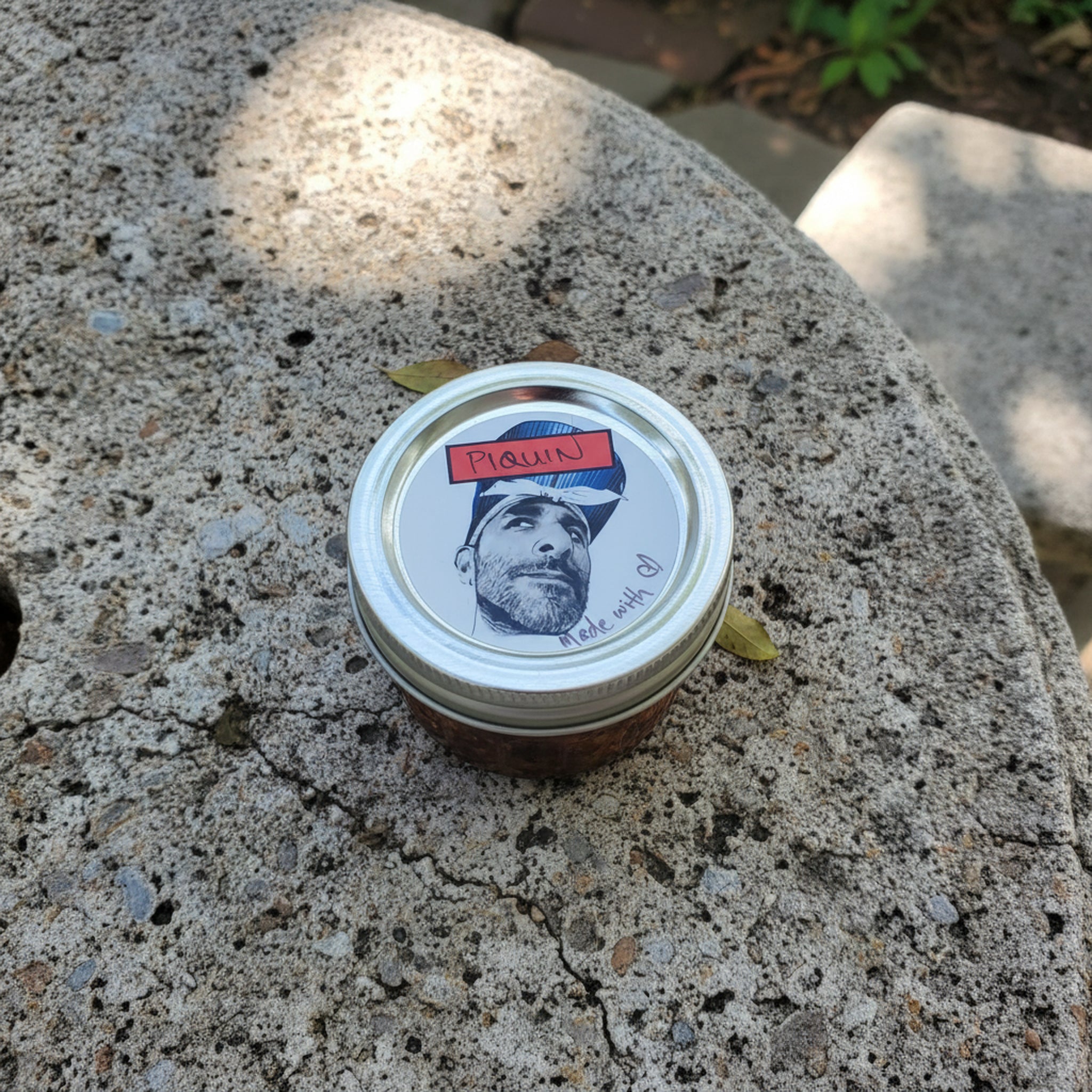 Chili Flores jar with a lid featuring a face illustration on a stone surface